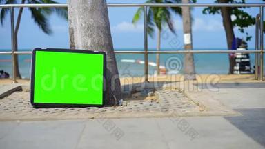 电视站在海滩上。 带绿色屏幕的电视。 你可以用你想要的镜头或图片替换绿色屏幕